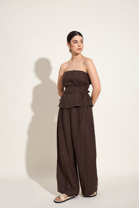 Woman wearing a brown strapless jumpsuit on a white background